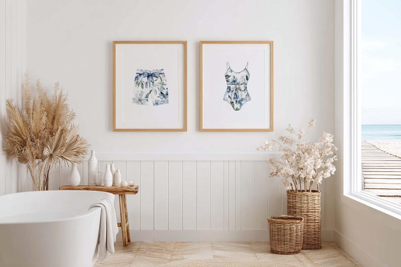 Add a touch of coastal elegance to your home with this coordinated set of two floral swimwear watercolor prints. Featuring a matching one-piece swimsuit and swim trunks adorned with soft blue florals and botanical accents, this collection blends vintage beach charm with sophisticated coastal style. Perfect for bathrooms, beach houses, lake cottages, dressing rooms, pool houses, and summer-inspired interiors.