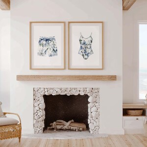 Add a touch of coastal elegance to your home with this coordinated set of two floral swimwear watercolor prints. Featuring a matching one-piece swimsuit and swim trunks adorned with soft blue florals and botanical accents, this collection blends vintage beach charm with sophisticated coastal style. Perfect for bathrooms, beach houses, lake cottages, dressing rooms, pool houses, and summer-inspired interiors.