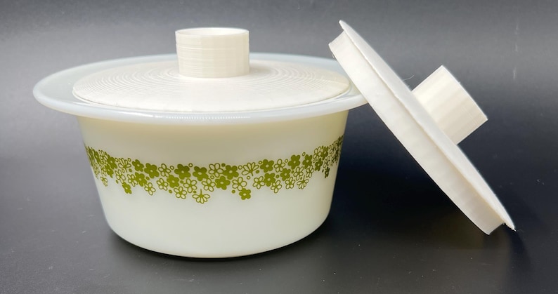 May include: White ceramic bowl with a green floral pattern and a matching lid. The lid has a knob on top.