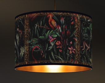 Pantalla de lámpara con estampado de pájaros tropicales y detalles dorados en el interior.