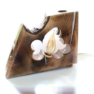 Op de afbeelding: Een houten lamp met een uniek ontwerp met een hartvormige uitsparing en een gloeilamp. De lamp is gemaakt van donker hout met een natuurlijke afwerking en heeft een wit snoer.
