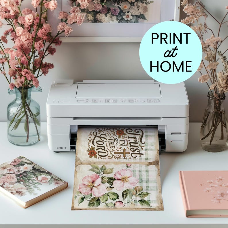 May include: A white printer is printing two floral-themed cards. The top card reads "Trust in the Lord" in a decorative font. The bottom card features pink flowers. The image also includes a light blue circle with the words "PRINT at HOME".