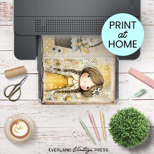Puede incluir: Una impresora imprime una ilustraci&oacute;n en acuarela de una ni&ntilde;a con largas trenzas y un vestido amarillo. La imagen est&aacute; rodeada de materiales de manualidades, incluyendo tijeras, bol&iacute;grafos y una taza de caf&eacute;. El texto "PRINT at HOME" es visible.