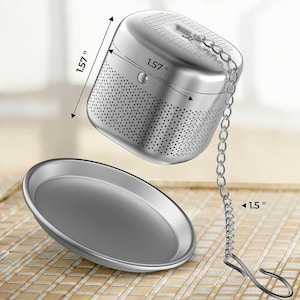 May include: Silver tea infuser with a lid and a chain. The infuser is 1.57 inches wide and 1.57 inches tall. The chain is 1.5 inches long. The infuser is sitting on a silver plate.