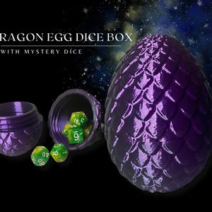 May include: Purple dragon egg dice box with a textured, scaly surface. The box is open, revealing green dice with white numbers. The text "Dragon Egg Dice Box with Mystery Dice" is visible at the top of the image.