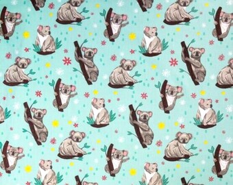 May include: A teal blue fabric with a repeating pattern of koalas sitting on branches. The koalas are brown and white, and the branches are brown. There are also small pink, red, and yellow flowers scattered throughout the pattern.