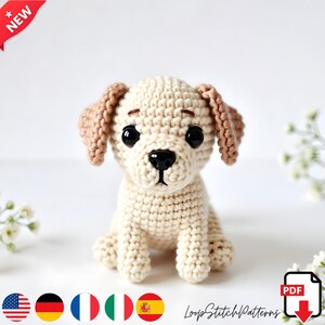 Peut inclure: Un chiot crocheté aux couleurs crème et marron, avec de grands yeux noirs et un nez noir. Le chiot est assis, les oreilles dressées. L'image comprend le texte "NEW" et le logo "LoopStitchPatterns".