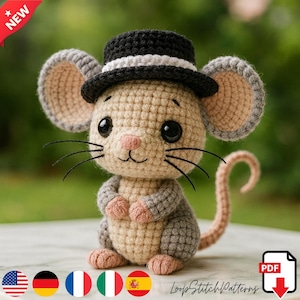 Puede incluir: Ratón de ganchillo con un sombrero de copa blanco y negro. El ratón tiene grandes ojos negros, largos bigotes y una nariz y orejas rosas. El ratón es de color beige, gris y rosa. La cola está enroscada. La imagen tiene una pancarta "NUEVO" en la esquina superior izquierda.