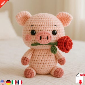 Può includere: Un maialino all'uncinetto rosa chiaro fatto a mano che tiene in bocca una rosa rossa. Il maiale ha occhi neri a bottone, guance rosa e un muso dettagliato. La rosa ha foglie e stelo verdi. Il maialino è seduto su una superficie bianca.