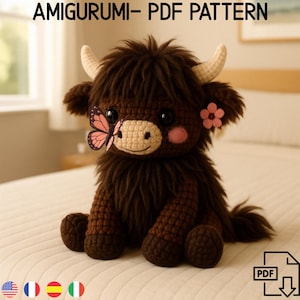 Op de afbeelding: Een bruine gehaakte amigurumi Highland Cow met een roze bloem en een vlinder op zijn gezicht. De koe zit op een wit beddengoed. De afbeelding bevat de tekst "AMIGURUMI - PDF PATTERN" en een downloadpictogram met de tekst "PDF".