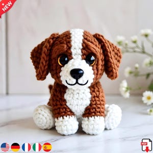 May include: A handmade crochet dog toy in brown and white. The dog has large, expressive eyes, a black nose, and a white stripe down its head. The toy is sitting on a marble surface.