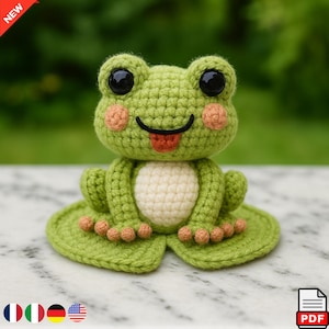 Könnte beinhalten: Eine handgefertigte Häkelfrosch in Grüntönen, mit cremefarbenem Bauch und pfirsichfarbenen Wangen. Der Frosch hat große schwarze Augen und eine rote Zunge, die herausragt. Der Frosch sitzt auf einem grünen Seerosenblatt.