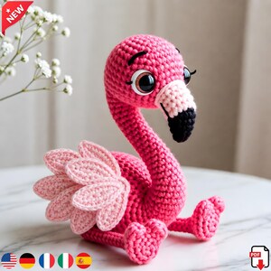 Könnte beinhalten: Ein handgefertigter rosa Häkelflamingo mit langem Hals, großen Augen und einem schwarz-weißen Schnabel. Der Flamingo hat einen hellrosa Flügel und sitzt. Das Wort "NEW" steht in einem roten Banner oben links.