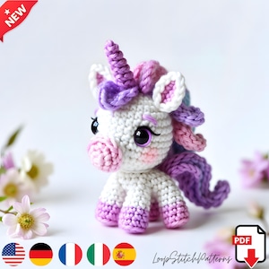 Könnte beinhalten: Ein gehäkeltes Einhorn-Spielzeug in Weiß, Rosa und Lila. Das Einhorn hat einen weißen Körper, eine rosa Schnauze und Hufe sowie eine lila Mähne und ein Horn. Die Augen sind groß und schwarz. Das Wort "NEW" steht in einem roten Banner oben links.