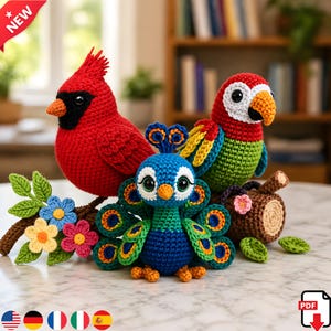 May include: A collection of handmade crochet birds, including a red cardinal, a parrot, and a peacock. The birds are perched on a decorative branch with flowers. The cardinal has a black mask and orange beak. The parrot is red, green, yellow, and blue. The peacock is blue and green.