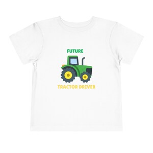 May include: White toddler t-shirt with a green tractor graphic and the words "FUTURE TRACTOR DRIVER" in green and yellow. The tractor has yellow wheels and a black exhaust pipe.