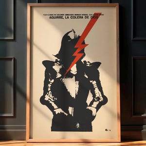 May include: Framed vintage movie poster for "Aguirre, The Wrath of God." The poster features a black and white illustration of a figure in armor with a red lightning bolt. The poster has text at the top.