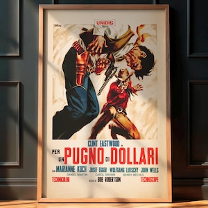 May include: Framed movie poster for "A Fistful of Dollars" featuring Clint Eastwood. The artwork depicts a dramatic scene with two figures in a gunfight, with text in Italian. The poster is in a wooden frame, displayed against a dark wall.