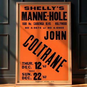 May include: A framed vintage poster with an orange background and black text. The poster advertises a performance at Shelly's Manne-Hole in Hollywood by John Coltrane, with dates in December '63. The poster is in a wooden frame.