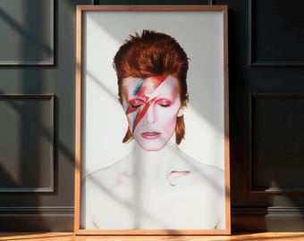 Puede incluir: Impresión artística enmarcada que presenta un retrato de una persona con cabello rojo y un rayo rojo y azul pintado en la cara. La obra de arte está en un marco de madera, sobre un fondo blanco y una pared oscura.