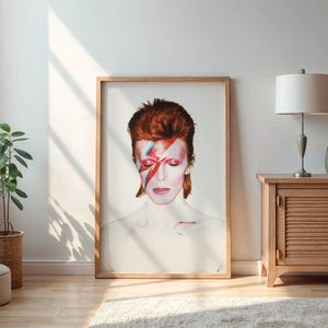 May include: A framed portrait of a person with red hair and a lightning bolt painted across their face. The artwork is displayed in a well-lit room with a wooden cabinet, a lamp, and a potted plant.