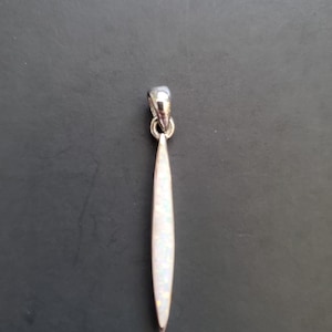 May include: A silver pendant with a white opal stone in the shape of a long, thin blade.