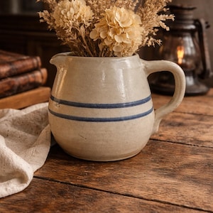 May include: A set of three ceramic mugs with a speckled, matte finish. The mugs are in shades of cream, light gray, and dark gray. Each mug has a simple, minimalist design and a rounded handle. The mugs are stacked on top of each other.