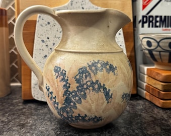 Jarra de cerámica vintage firmada, con diseño floral azul, estilo estudio.