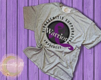 May include: Gray t-shirt with a purple ribbon and the text "Hidradenitis Suppurativa Warrior Awareness".