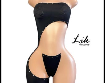 Könnte beinhalten: Schwarzes einteiliges Tanzkostüm mit Cut-Out-Design und Strasssteinen. Das Outfit besteht aus einem trägerlosen Oberteil und einem hochgeschnittenen Bein.