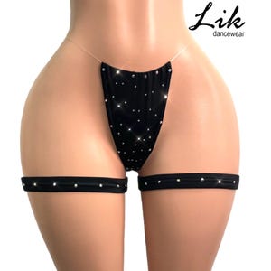 Könnte beinhalten: Schwarzes Dessous-Set mit Strasssteinen. Das Set besteht aus einem String und zwei Strumpfhaltern. Die Strumpfhalter sind mit Strasssteinen verziert.