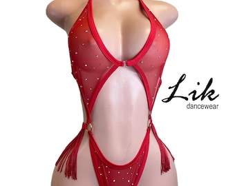 Puede incluir: Traje de baile rojo con cuello halter y adornos de pedrería. La tela transparente presenta un diseño de ojo de cerradura y detalles de anillos dorados. Borlas cuelgan de los lados. El texto "Lik dancewear" está impreso.