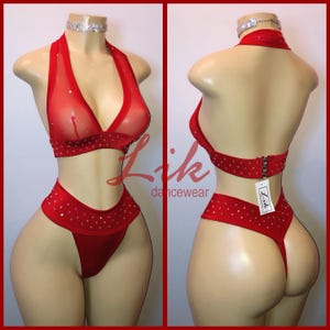 May include: Red lingerie set with a sheer mesh top and a high-cut bottom. The set is adorned with rhinestones and features a halter neck style. The brand name "Zik dancewear" is visible on a tag.