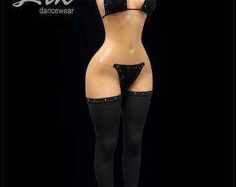 Puede incluir: Conjunto de ropa de baile negro con detalles de pedrería. El conjunto incluye un bikini halter, un tanga y leggings hasta el muslo con bajos acampanados. La marca "Lik dancewear" está en la esquina superior izquierda.