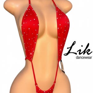 May include: Red dancewear with rhinestone embellishments. The halter-style top and bottom are connected by thin straps. The dancewear is on a mannequin. The brand name "Lik dancewear" is visible.