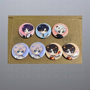 May include: Eight circular pin badges with anime-style character designs. Each badge displays a different character with varied hair colours and outfits. The badges are arranged on a brown cardboard surface.