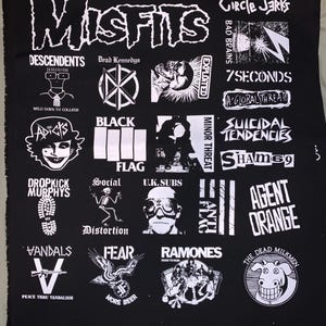 May include: Black fabric featuring white logos of punk rock bands, including Misfits, Descendents, Dead Kennedys, Exploited, Circle Jerks, and Ramones. Other bands include Dropkick Murphys, Agent Orange, and Suicidal Tendencies. The text "Peace Thru Vandalism" is also visible.