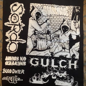 May include: Black and white embroidered patch with the text "GULCH" in large, bold letters. The patch also features a graphic of a hooded figure holding a bag, a police officer, and the text "THERE IS NO ESCAPE" and "BUDD DWYER".