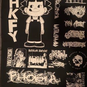 May include: Black fabric patch featuring various white graphic designs. Includes a cartoon girl, band logos, and the text "HKFX", "VIOLENCIA", "INALME", "METHZAAAR", "HARM DONE", "INSECT GRINDER", "RANCIO STENCH GORE", and "PHOBIA".