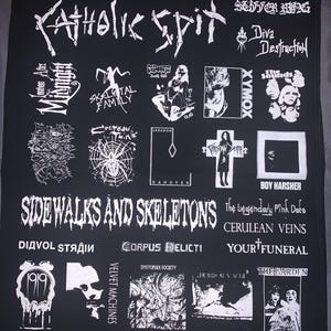 May include: Black fabric with white graphics featuring band names and logos, including "Catholic Spit," "Sidewalks and Skeletons," and "Xymox." The design includes various illustrations and text arrangements.