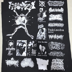 May include: Black fabric featuring multiple white graphic designs and text. Designs include a frog-like creature, band logos, and the words "Yakisoba" and "ROACEWHORE". The fabric is likely intended for patches or DIY projects.