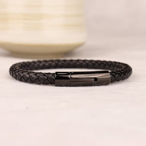 May include: A black leather bracelet with a black metal clasp.
