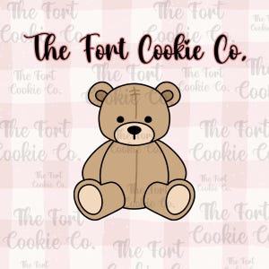 May include: A brown teddy bear cookie cutter with a black outline. The bear has a round black nose and small black eyes. The text "The Fort Cookie Co." is at the top of the image. The background is a pink and white checkered pattern.