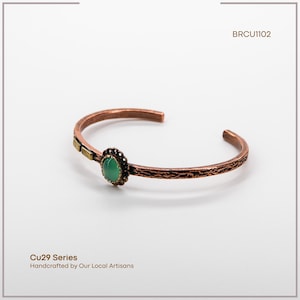 Pu&ograve; includere: Bracciale a polsino in rame con fascia strutturata e pietra verde ovale centrale. Il bracciale ha un accento decorativo color oro e fa parte della serie Cu29, realizzato a mano da artigiani locali. Il codice prodotto &egrave; BRCU1102.