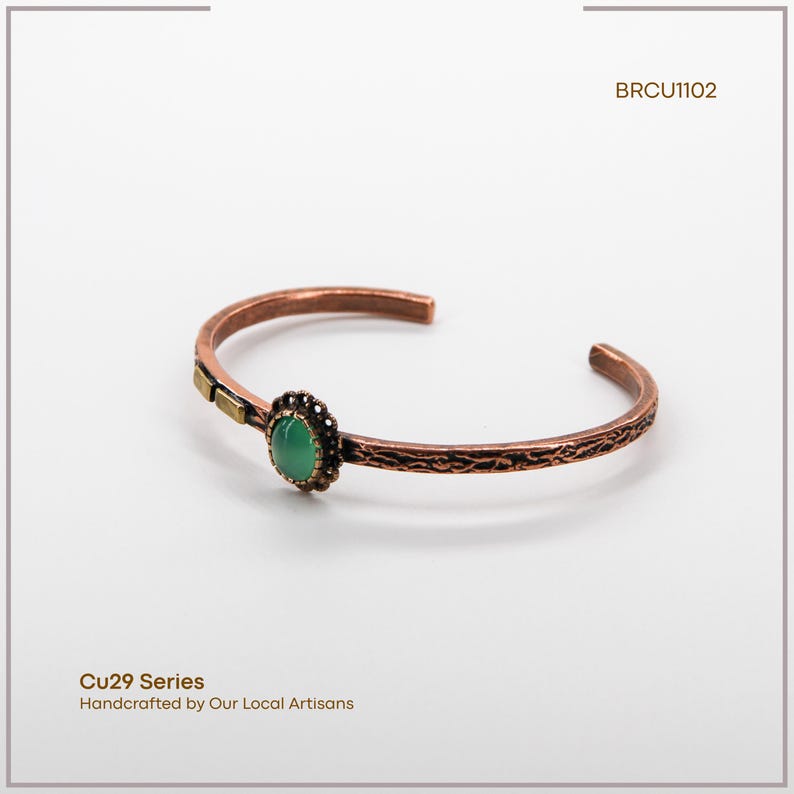 Pu&ograve; includere: Bracciale a polsino in rame con fascia strutturata e pietra verde ovale centrale. Il bracciale ha un accento decorativo color oro e fa parte della serie Cu29, realizzato a mano da artigiani locali. Il codice prodotto &egrave; BRCU1102.