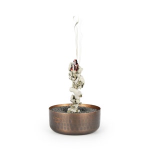 May include: A copper incense burner with a hammered finish and the word "COHO" engraved on the side. White incense is burning in the burner, producing a plume of smoke.