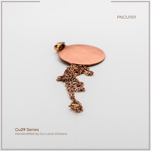 May include: A copper pendant necklace featuring a circular pendant and a fine chain. The necklace is handcrafted by local artisans, as indicated by the text "Cu29 Series Handcrafted by Our Local Artisans". The product code is "PNCU1101".
