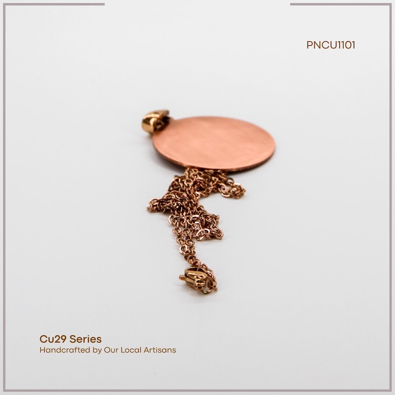 May include: A copper pendant necklace featuring a circular pendant and a fine chain. The necklace is handcrafted by local artisans, as indicated by the text "Cu29 Series Handcrafted by Our Local Artisans". The product code is "PNCU1101".