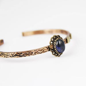 May include: A copper bracelet with a textured finish and a blue lapis lazuli stone set in a brass bezel.