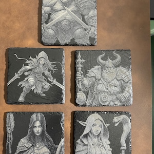 Op de afbeelding: Vier zwarte leisteen onderzetters met gegraveerde afbeeldingen van fantasy-personages. De onderzetters tonen een krijger, een tovenaar, een dief en een orc.